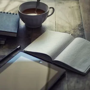 Meine Morgenroutine. Zu sehen ist ein Notizbuch, eine Tasse mit Getränk und ein Tablet